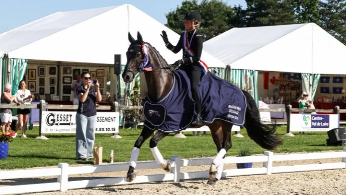 Pauline Basquin et Sertorius de Rima Z célèbrent leur titre de champions de France Pro Élite de dressage 2026 à Vierzon lors du tour d'honneur.