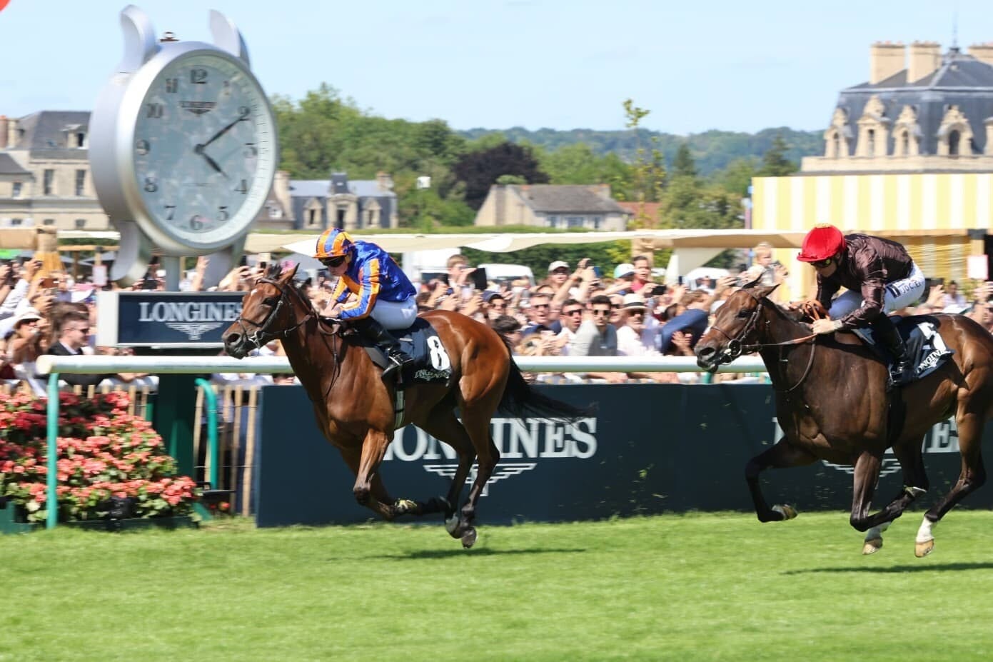 Photo-finish officielle du Prix de Diane Longines 2026. À gauche, la pouliche gagnante Diamond Necklace avec Ryan Moore passe le poteau en tête juste devant Pink Pantera au pied de la grande horloge.