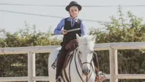 Jeune cavalier en tenue traditionnelle d'équitation de travail Camargue tenant une garroche lors des Championnats de France 2026 à Aimargues.
